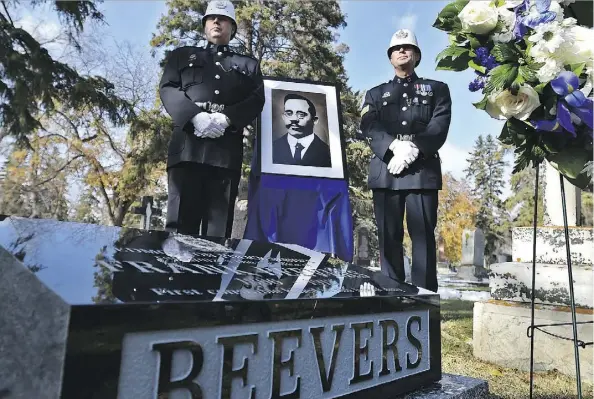  ?? ED KAISER ?? Sgt. Cliff Reimer, left, and retired Sgt. Darren Zimmerman — dressed in period clothing — stand next to a portrait of Const. Frank Beevers, the first Edmonton police officer killed in the line of duty. Beevers was honoured with a monument dedication Thursday after it was discovered his grave was left unmarked at the Edmonton Cemetery for nearly a century. It is believed the grave was originally marked with a wooden cross.