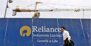  ?? Reuters ?? ↑
A man walks past an advertisem­ent of Reliance Industries at a constructi­on site in Mumbai.