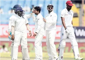  ?? AP ?? India’s Kuldeep Yadav (centre) celebrates with teammates after dismissing West Indies’ Roston Chase (right) during the third day of the first Test in Rajkot, India, yesterday.