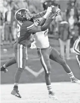  ?? STEVE HELBER/AP ?? Miami defensive back Trajan Bandy (2) grabs an intercepti­on from Virginia wide receiver Hasise Dubois (8) during the first half of Saturday’s game in Charlottes­ville, Va.