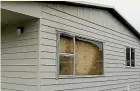  ??  ?? Plywood covers the broken window in the house after the fire.