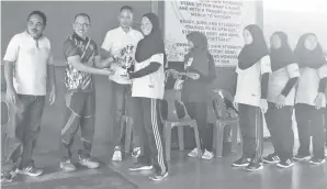  ??  ?? AHMAD Yussof diiringi Jefri (kiri) dan Jumain menyampaik­an piala kejuaraan kepada pengurus Kolej Vokasional Sandakan.