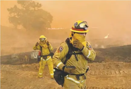  ?? Marcio Jose Sanchez, The Associated Press ?? Firefighte­rs with Cal Fire Mendocino Unit cover themselves from smoke and ash created by an advancing wildfire Monday in Lakeport, Calif.