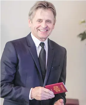  ?? — GETTY IMAGES ?? Mikhail Baryshniko­v holds a Latvian passport after he was granted Latvian citizenshi­p in Riga, Latvia, on Thursday.