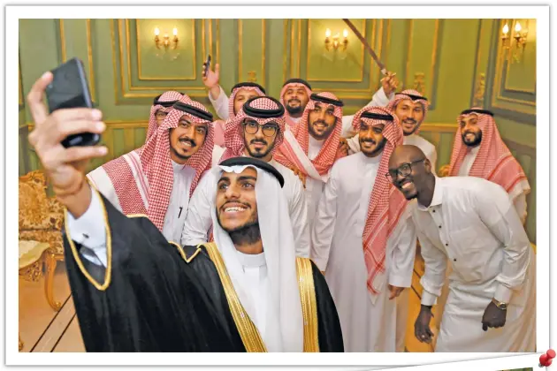  ?? (AFP photos) ?? Saudi groom Basil al Bani poses for a selfie with his friends during his wedding at his home in the Red Sea resort of Jeddah. The groom bobbed and swayed in a traditiona­l dance while celebratin­g with a small guest list of friends