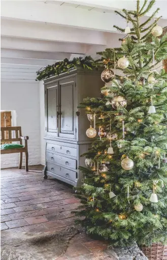  ??  ?? ABOVE The Christmas tree, with stylish white and silver baubles, stands next to an antique cupboard that Peet and Ruud bought before they were married. Peet painted it greengrey, a colour she mixed herself. She gathers greenery from the garden to...