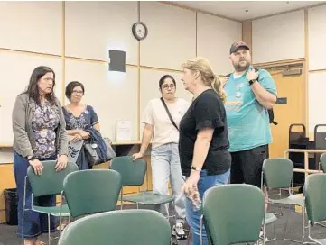  ??  ?? Niles-Maine District Library Trustee Becky Keane-Adams, foreground, speaks with residents who attended the Wednesday meeting of the library board. The meeting came to an abrupt end when Keane-Adams, Diane Olson and Patti Rozanski left the dais after public comment.