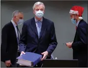  ?? (AP/Olivier Hoslet) ?? A colleague wears a Christmas hat as European Union chief negotiator Michel Barnier (center) carries a binder of the Brexit trade deal during a special meeting Friday at the European Council building in Brussels.