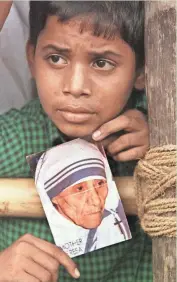  ?? JOHN MOORE / ASSOCIATED PRESS ?? An Indian boy holds a portrait of Mother Teresa as he waits for the return of her procession from the funeral Mass in Netaji Indoor Stadium in Calcutta on Sept. 13, 1997.