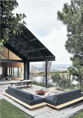  ??  ?? From the front of the house, the stylised silhouette of its contempora­ry barn aesthetic is most clearly revealed. The outdoor entertainm­ent area is sheltered from the sun and wind by a blackened wood pergola-style structure.