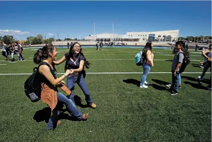  ?? PHOTOS BY LUIS SÁNCHEZ SATURNO/THE NEW MEXICAN ?? Eighth graders Wendy Muñoz Hernandez, 13, left, and Perla Arzabala, 13, dance Tuesday during a break on the new field at Milagro Middle School. The new school opened for its first day.