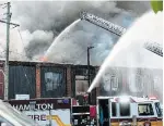  ?? BARRY GRAY THE HAMILTON SPECTATOR ?? Water is poured on the fire at the former Mr. Used on Barton Street East.