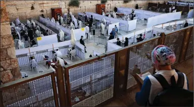  ?? (AP/Oded Balilty) ?? Ultra-Orthodox Jews pray Thursday at the Western Wall in Jerusalem’s Old City in sectioned-off areas that allow a maximum of 20 worshipers, in line with government measures.