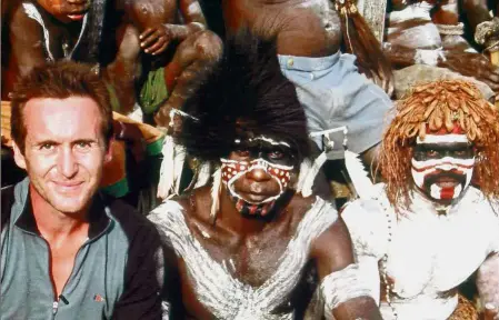  ??  ?? Different worlds: Parry sitting with former cannibals in West Papua while filming ‘ Tribe’ on Discovery Channel, one of the many tribes he has sought for his documentar­ies.