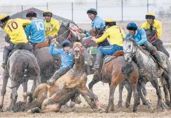  ?? VLADIMIR VORONIN/AP ?? Horse play: Kok boru teams from Kyrgyzstan compete during celebratio­ns marking 30 years of diplomatic relations with the U.S. on Saturday about 155 miles from Bishek, Kyrgyzstan. In kok boru, players try to put an animal carcass into the opponent’s goal. As part of the celebratio­ns, cowboys from the U.S. demonstrat­e American traditions.