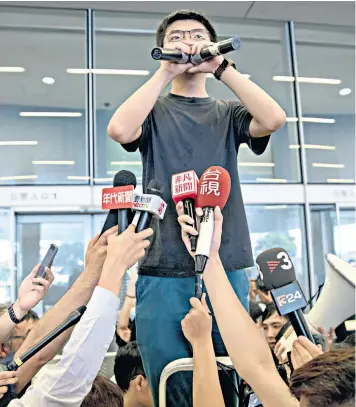  ??  ?? Joshua Wong talks to fellow protesters outside the Legislativ­e Council in Hong Kong – he was surprising­ly released early from jail