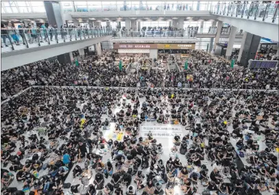  ?? Vincent Thian The Associated Press ?? Protesters stage a sit-in Monday in the arrival hall of Hong Kong Internatio­nal Airport. The airport suspended all flights Monday because of the ongoing pro-democracy protest. Beijing characteri­zed the movement as something approachin­g “terrorism.”