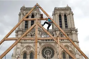  ?? (AP photo/Francois Mori, File) ?? On Spet. 19, 2020, Charles, one of the carpenters puts the skills of their medieval colleagues on show on the plaza in front of Notre Dame Cathedral in Paris, France. France’s Notre Dame Cathedral’s reconstruc­tion is progressin­g enough to allow its reopening to visitors and masses at the end of next year, less than six years after the after the shocking fire that tore through its roof, French officials said as an exhibit pays tribute to hundreds of artisans working on it.