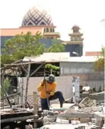  ??  ?? RATAKAN DENGAN TANAH: Seorang pekerja membongkar bangunan liar di Sememi Jaya kemarin.