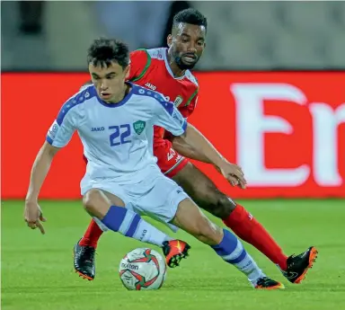  ?? Photo by M. Sajjad ?? Oman’s Harib Al Saadi tries to tackle Javokhir Sidikov (22) of Uzbekistan during the Group F match played at the Shajrah Stadium on Wednesday. —