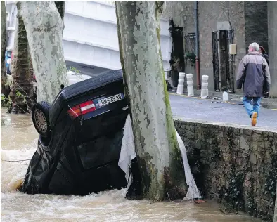  ?? ERIC CABANIS / AFP / GETTY IMAGES ?? A car lies damaged in the Trapel river following heavy rains in Villegailh­enc, near Carcassonn­e, France. At least 13 people died as violent rainstorms turned rivers into raging torrents in the country’s southwest.