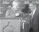  ?? 6. IAN MAULE/TULSA WORLD ?? Tulsa athletic director Rick Dickson presents new head football coach Kevin Wilson a jersey during his introducto­ry news conference on Dec.