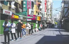  ?? (Aly Song/Reuters) ?? SHANGHAI RESIDENTS stand on a street on Sunday waiting to be tested for coronaviru­s.