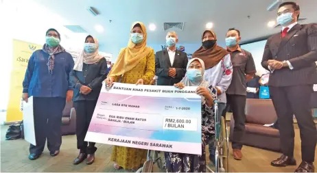  ??  ?? Fatimah (third left) presenting the special aid in the form of a mock cheque to dialysis patient Lara Wahab, witnessed by others.