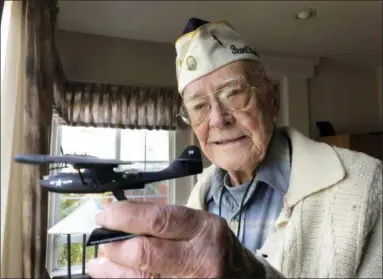  ?? ERIC RISBERG — THE ASSOCIATED PRESS ?? At his home in Napa, California, retired U.S. Navy Cmdr. Don Long holds a replica of the military seaplane on which he was standing watch when Japanese warplanes attacked Hawaii 77 years ago.