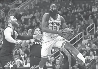  ?? ROSS D. FRANKLIN/AP ?? Houston Rockets guard James Harden (13) looks to pass the ball as he gets past Suns center Aron Baynes, left, and guard Devin Booker on Saturday.
