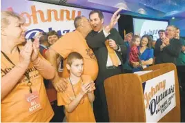  ?? KENNETH K. LAM/BALTIMORE SUN ?? Johnny Olszewski Jr., center, gets a kiss from his father, John Olszewski Sr. He was one of three Democrats to win key county executive seats.