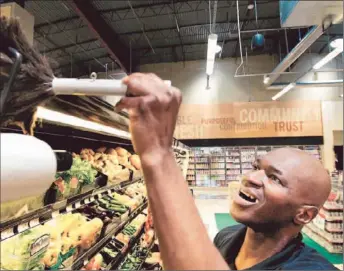  ?? Photograph­s by Christina House For The Times ?? CLARENCE WILBURN works at Fresco Community Market in Montecito Heights. He’s one of 12 people the store has hired through a program on skid row. Market owner Jon Murga says they’re great employees.
RETAIL