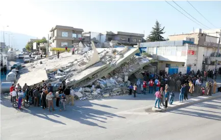  ?? (Khalil Dawood/TNS) ?? RESIDENTS AND RESCUE workers gather near a collapsed building in the town of Darbandikh­an in northern Iraq on Tuesday, after an earthquake along the northern border between Iran and Iraq on Sunday left at least 454 people dead and more than 7,800...