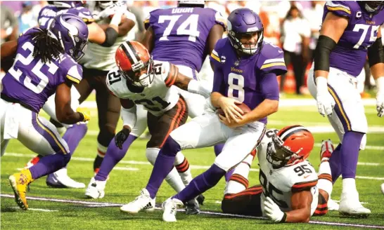  ?? BRUCE KLUCKHOHN/AP ?? Vikings quarterbac­k Kirk Cousins feels the heat from Browns cornerback Denzel Ward (21) and defensive end Myles Garrett during the second half.