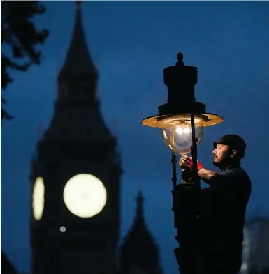  ?? Photos AFP ?? A British Gas engineer services a gas-powered lamp near the Houses of Parliament in central London this month.