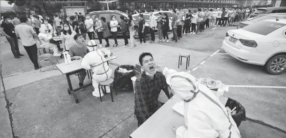  ?? CHEN XUEZI / FOR CHINA DAILY ?? Employees from companies in Caidian district, Wuhan, line up to undergo nucleic acid testing for the coronaviru­s.