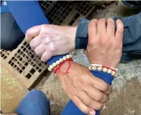  ?? AFP ?? Rescuers in Mae Sai, Chiang Rai province, lock hands with a caption (not seen) which reads: ‘We Thai and the internatio­nal teams join forces to bring the young Wild Boars home’. —