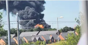  ??  ?? ●●A plume of smoke and flames rise over the roofs of houses surroundin­g the industrial estate