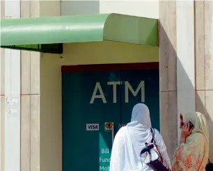  ?? — AFP ?? Women wait outside a bank ATM in Islamabad. The Financial Inclusion Plan aims to raise the number of customers with access to bank accounts and services to 50 per cent of the adult population.