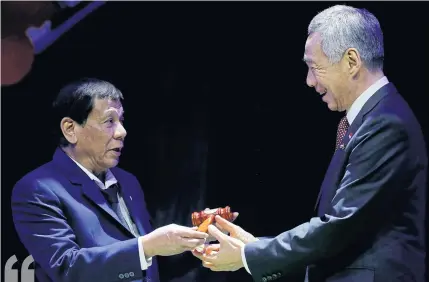  ?? AFP ?? Philippine President Rodrigo Duterte, left, hands over the gavel to Singapore Prime Minister Lee Hsien Loong during the transfer of the Asean chairmansh­ip at the closing ceremonies of the 31st Asean Summit in Manila on Nov 14.