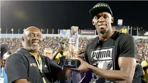  ?? AP ?? Jamaica’s Usain Bolt receives a special award from his coach, Glen Mills, before competing in the ‘Salute to a Legend’ 100 metres Racers Grand Prix. —