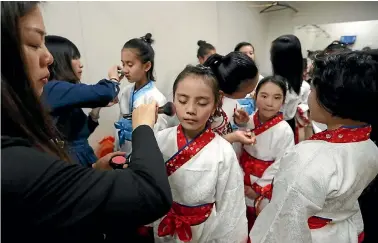  ?? MARTIN DE RUYTER ?? Xiao Lichen, left applies make-up to Zhang Xiqian back stage, at the Theatre Royal, before the performanc­e by Minzhu Road Primary School and Guiya Road Primary School from China. The performanc­e was part of the China Week in Nelson.