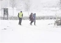  ??  ?? Heads down Off to work in the treacherou­s conditions