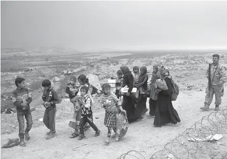  ?? AP Photo/
Marko Drobnjakov­ic ?? ■ Internally displaced Iraqis clear a checkpoint Wednesday in Qayara, some 50 kilometers south of Mosul, Iraq. Islamic State militants have been going door to door in farming communitie­s south of Mosul, ordering people at gunpoint to follow them north...