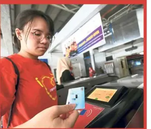  ??  ?? Commuter Chia Zhi Xin using her identity card at the ampang LrT station to access the My100 unlimited travel pass. — Bernama