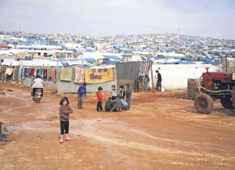  ??  ?? Children gather outside their makeshift shelters following torrential rain that affected a camp for displaced people near the town of Atme, close to the Turkish border, in Syria’s mostly opposition-held northern Idlib province, Jan. 10.