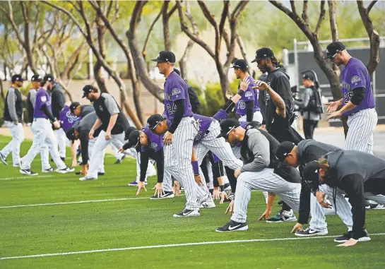  ?? Andy Cross, The Denver Post ?? The Rockies do some stretching on their first day of full-squad workouts Monday at Salt River Fields in Scottsdale, Ariz. They open Cactus League play Saturday against the Arizona Diamondbac­ks. The regular season stretches from March 28 to Sept. 29.