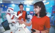  ?? CHEN XIAOGEN / FOR CHINA DAILY ?? A visitor shakes hands with a robot during a science and technology week in Beijing.