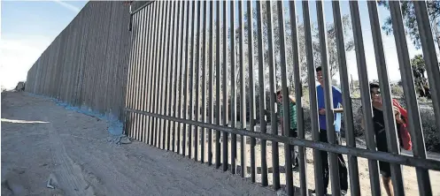  ?? GREGORY BULL/AP ?? Isolamento. Meninos observam do outro lado da parte antiga da cerca: novo acordo prevê US$ 1,4 bilhão para ampliação da barreira