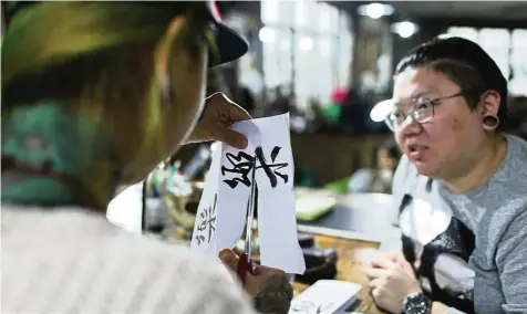  ??  ?? Web designer and tattoo enthusiast Wang Qi (right) is contemplat­ing new body art designs with her tattoo artist. — Photos: AFP